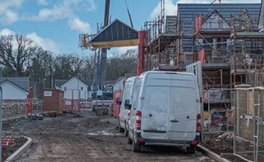 Modern,Scottish,Residential,Building,Site,At,Various,Levels,Of,Construction Modern Scottish Residential Building Site at various levels of construction and completion surrounded by scaffolding fencing and other materials. A Pre-constructed Roof is being lifted with a Crane.