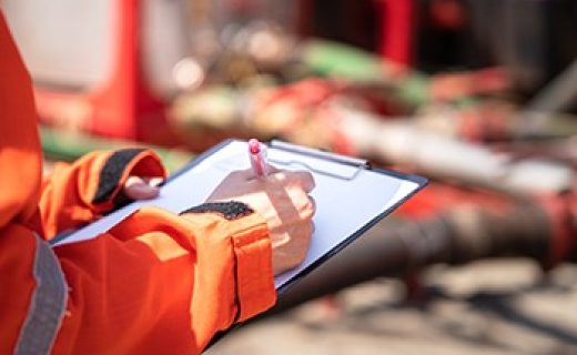 Safety,Officer,Or,Supervisor,Is,Writing,Note,On,The,Checklist Safety officer or Supervisor is writing note on the checklist paper during perform audit and inspection in oil field operation. Close-up action and selective focus photo.