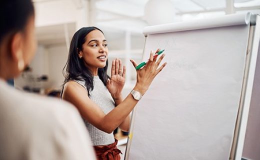 Woman, mentor and whiteboard in office for training, teaching and learning for skill or career development. People, employee and coach or leader at workshop with internship program and motivation