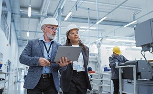 Two,Professional,Heavy,Industry,Engineers,Wearing,Hard,Hats,At,Factory. Two Professional Heavy Industry Engineers Wearing Hard Hats at Factory. Walking and Discussing Industrial Machine Facility, Working on Laptop. African American Manager and Technician at Work.